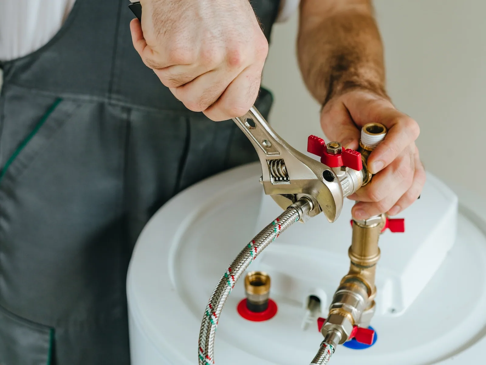 EP Plumbing, Heating & Air technician tightening the supply line fitting on top of a water heater