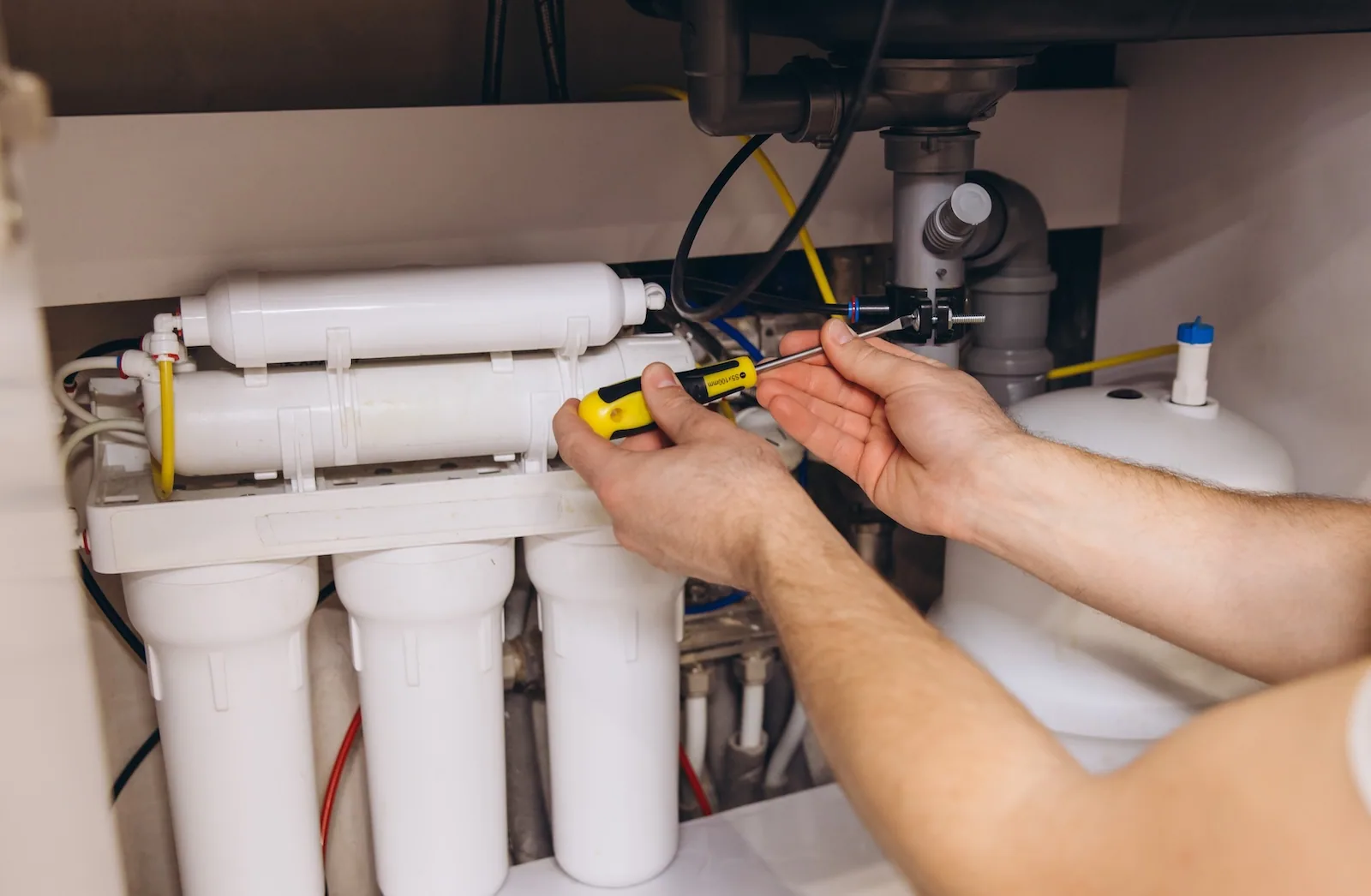 EP Plumbing, Heating & Air technician installing a reverse osmosis unit under a kitchen sink